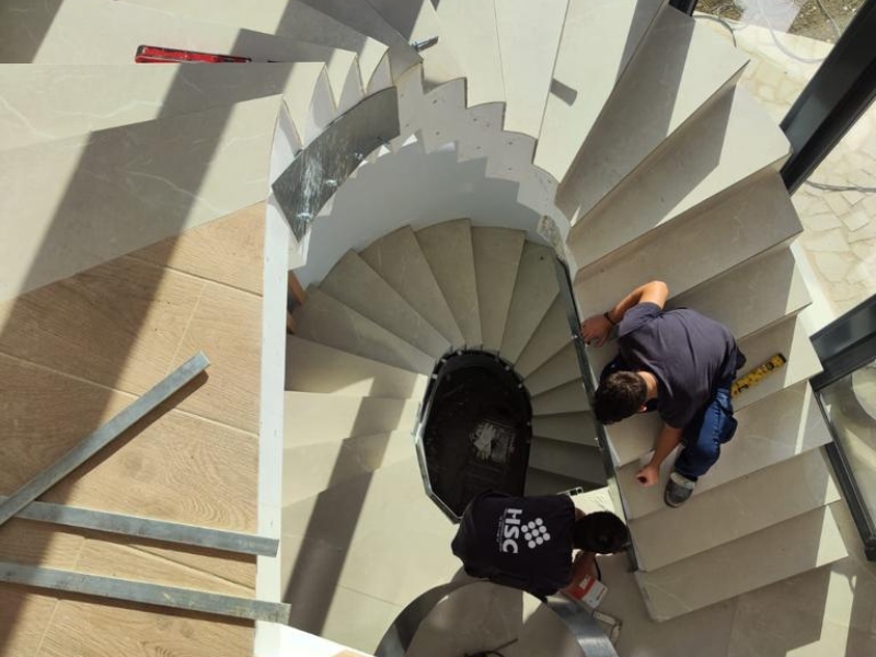 Trabajadores instalando escalera de caracol en vivienda unifamiliar con diseño moderno