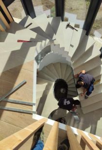 Trabajo en Altura: Seguridad y Coordinación en la Construcción Dos trabajadores de la construcción asegurando cadenas para el levantamiento de materiales en una obra en altura. Ambos llevan equipo de protección, como cascos y guantes, y colaboran estrechamente para garantizar la correcta instalación de los elementos en la estructura. El ambiente refleja el enfoque en seguridad y precisión en las tareas de elevación.