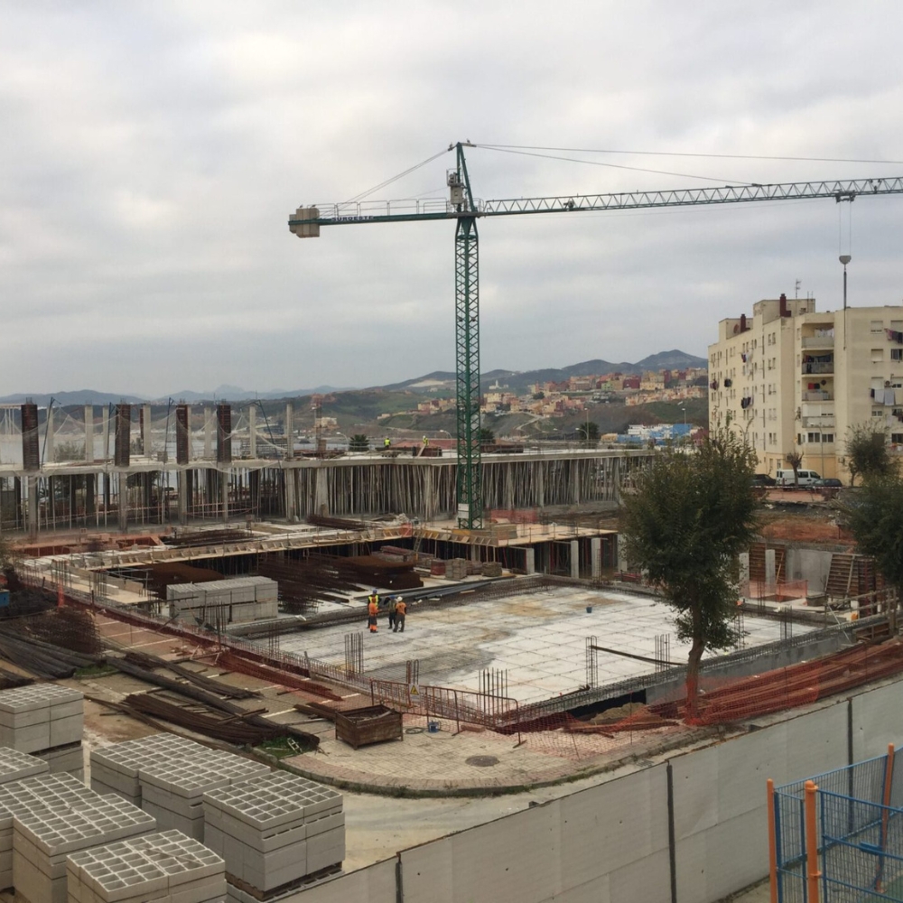 Vista general de la estructura en construcción del Pabellón Deportivo Díaz Flor en Ceuta, con encofrados y grúa de obra. Proyecto de infraestructura deportiva ubicado en un área residencial urbana, ejecutado por Estructuras Mañez.
