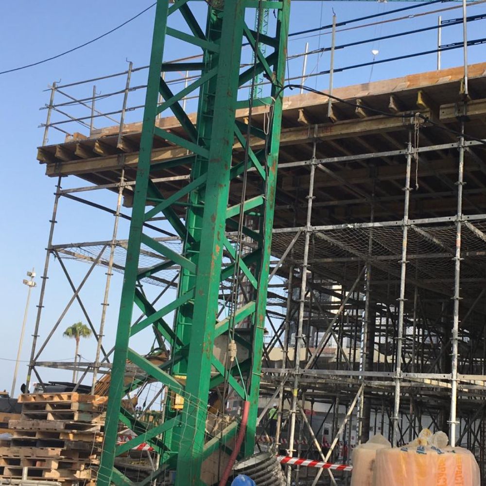 Vista de los andamios y estructura de soporte en la construcción de la residencia Tiempo Libre en Cádiz, con grúa y redes de seguridad en el sitio