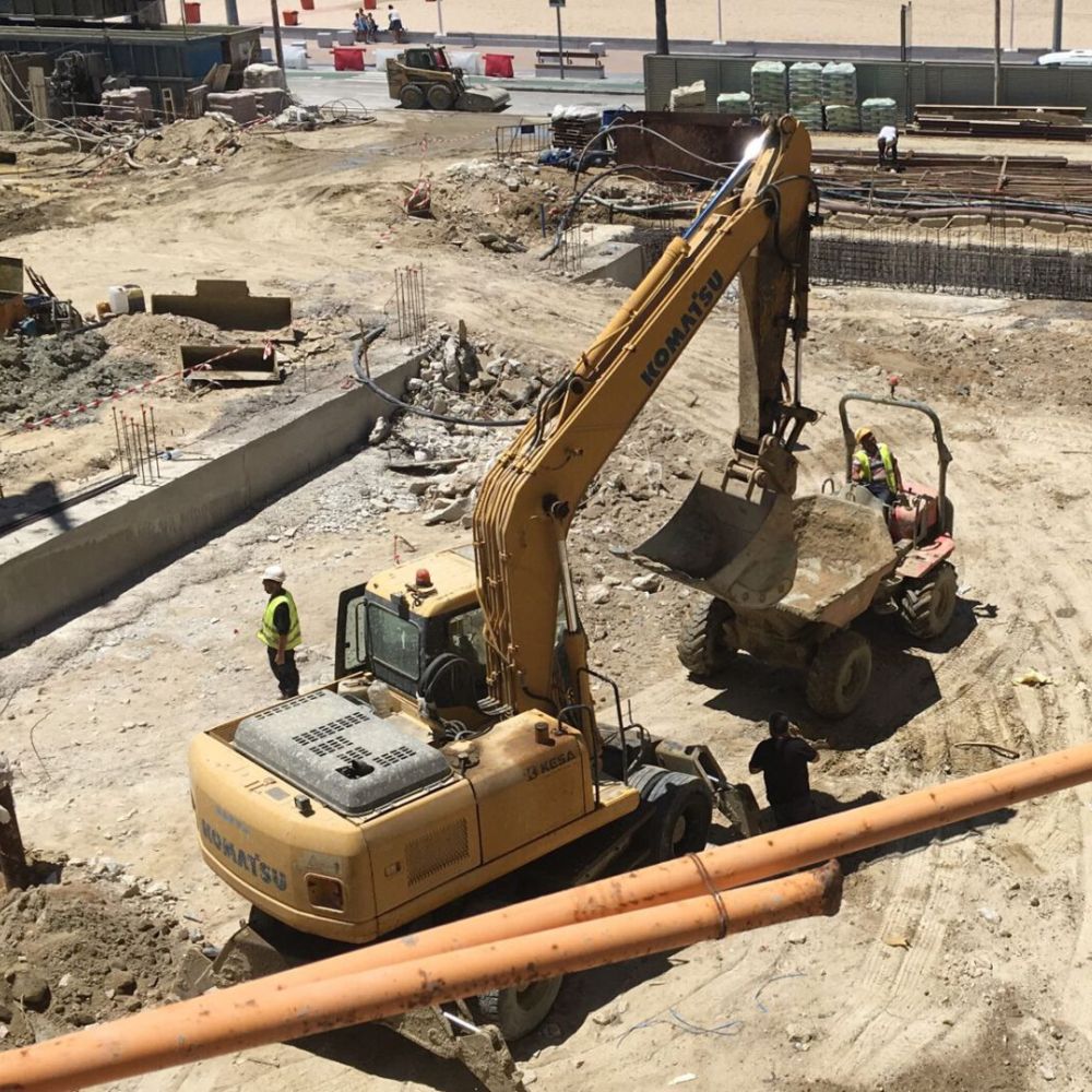 Maquinaria pesada realizando excavación y movimiento de tierra en el terreno de la residencia Tiempo Libre en Cádiz, con operarios supervisando los trabajos
